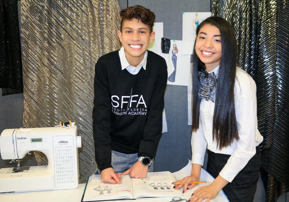 Two people standing next to a table with some papers